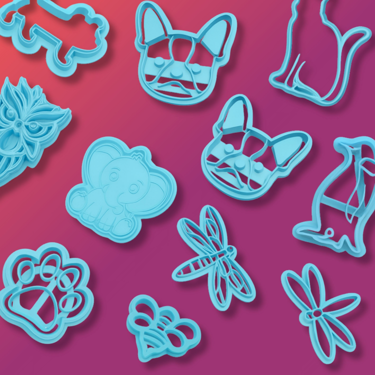 Animal-themed blue polymer clay cutters including dog faces, cats, penguins, an elephant, owl, paw print, dragonflies, and a bee. Set against a pink to red gradient background.