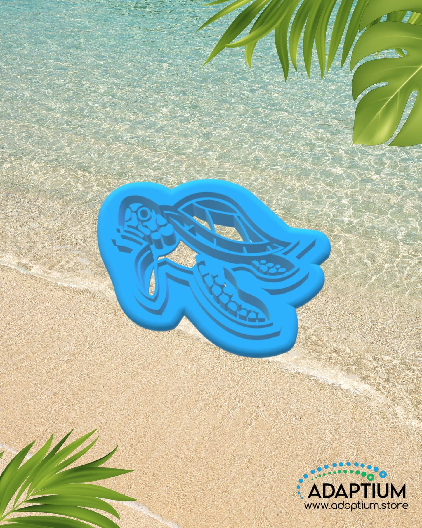 Turtle shaped polymer clay cutter placed on sandy beach background with ocean water and tropical leaves.