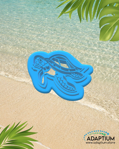 Turtle shaped polymer clay cutter placed on sandy beach background with ocean water and tropical leaves.