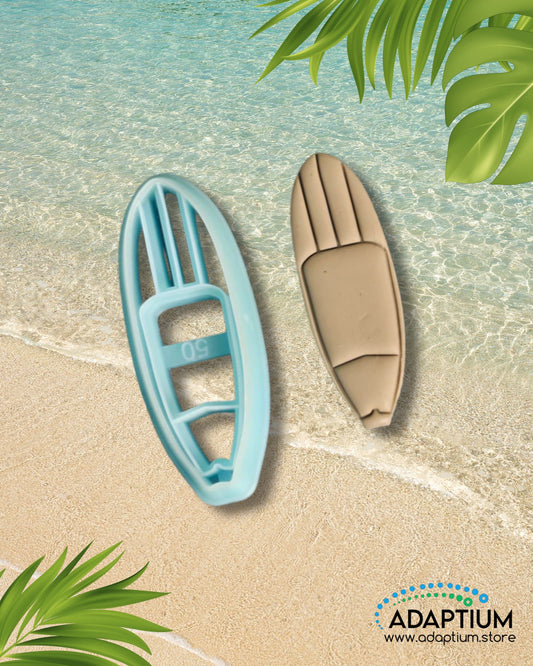Blue surfboard-shaped polymer clay cutter with matching tan clay surfboard piece displayed on a beach background with tropical leaves.