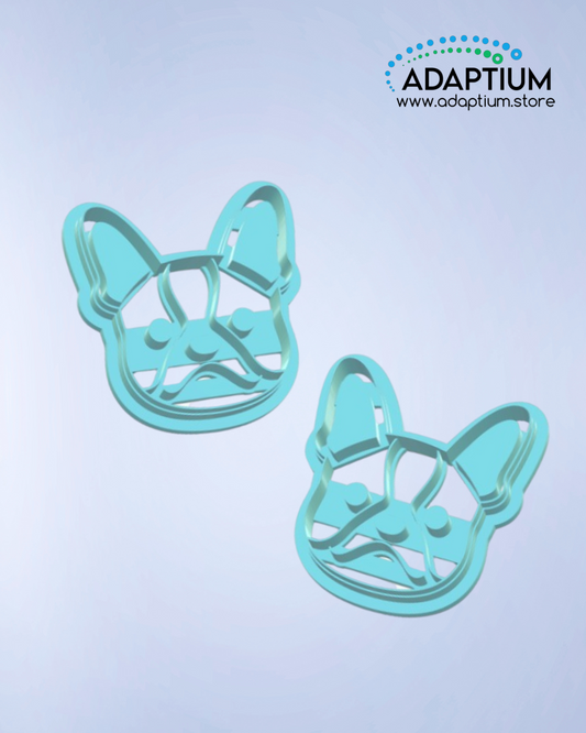 A pair of blue polymer clay cutters shaped like a French Bulldog's face, designed with cutout details for ears, eyes, and mouth. Displayed on a light gradient background.