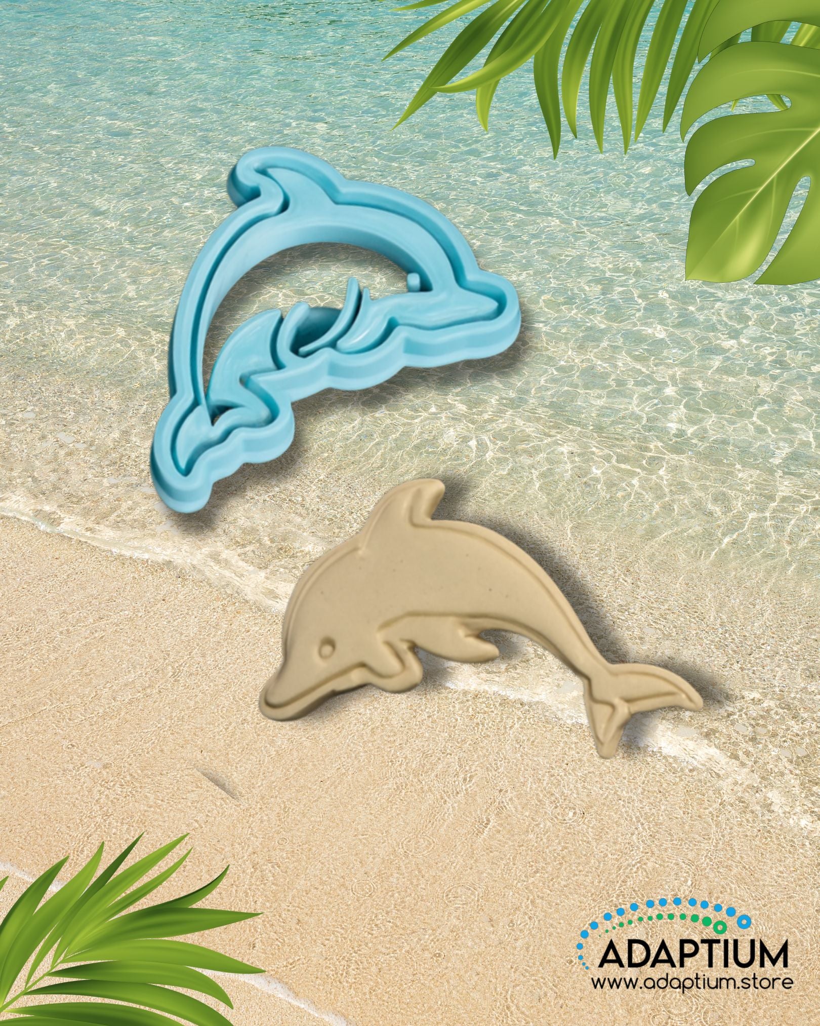 Blue dolphin polymer clay cutter with matching tan clay dolphin piece displayed on a sandy beach background with turquoise ocean waves and tropical leaves.