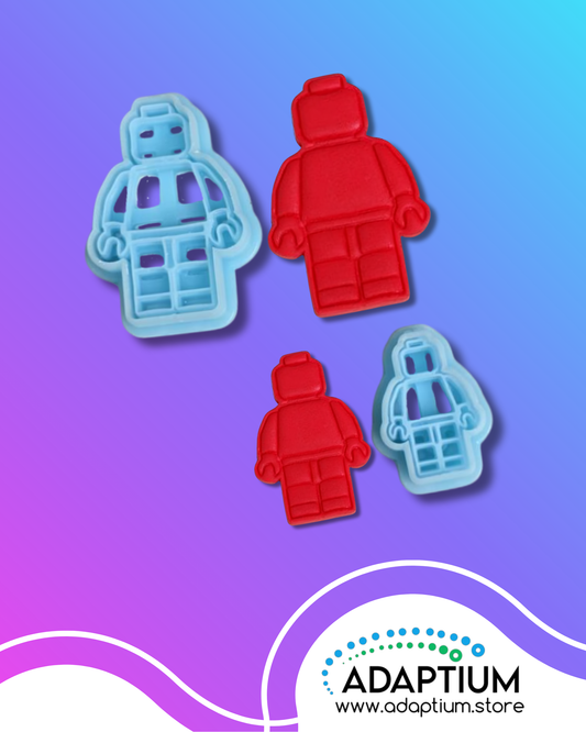Polymer clay cutters in the shape of toy figures, shown in blue and paired with matching red clay cutouts, displayed on a purple and blue gradient background with the Adaptium logo.