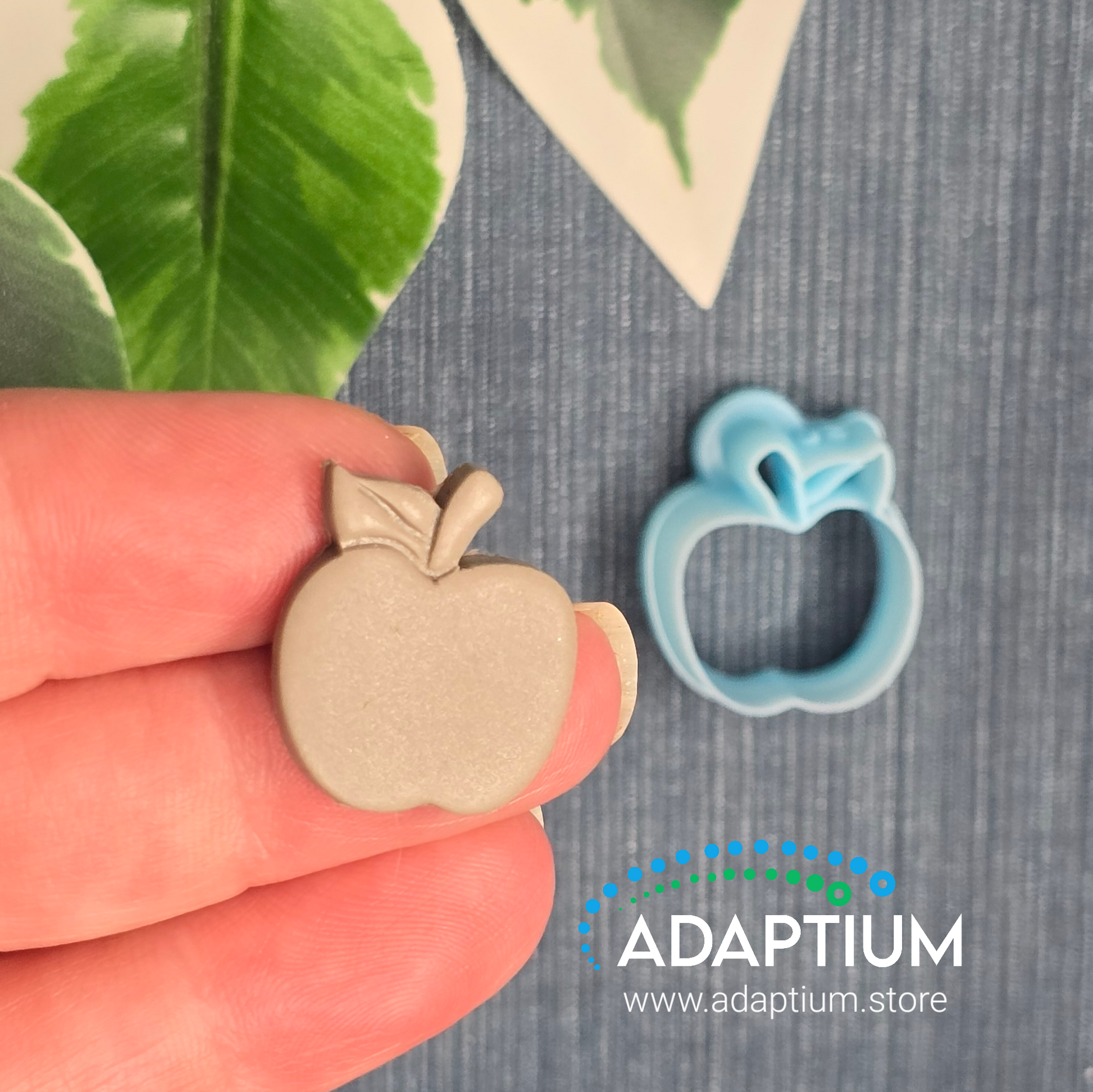 Hand holding a sharp, sky blue apple with stem & leaf resin cutter for polymer Clay