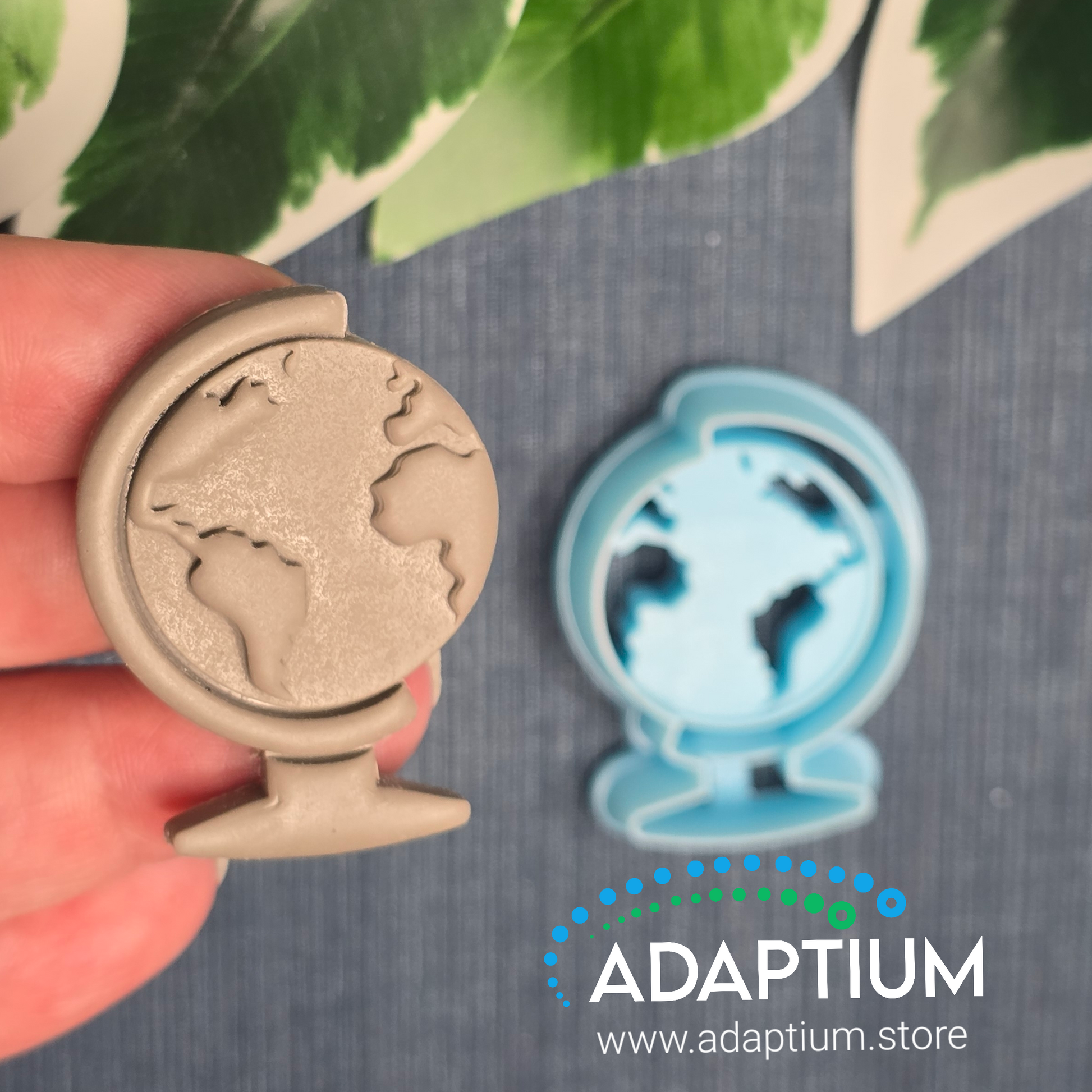 Hand holding a sharp, sky blue World globe resin cutter for polymer Clay 